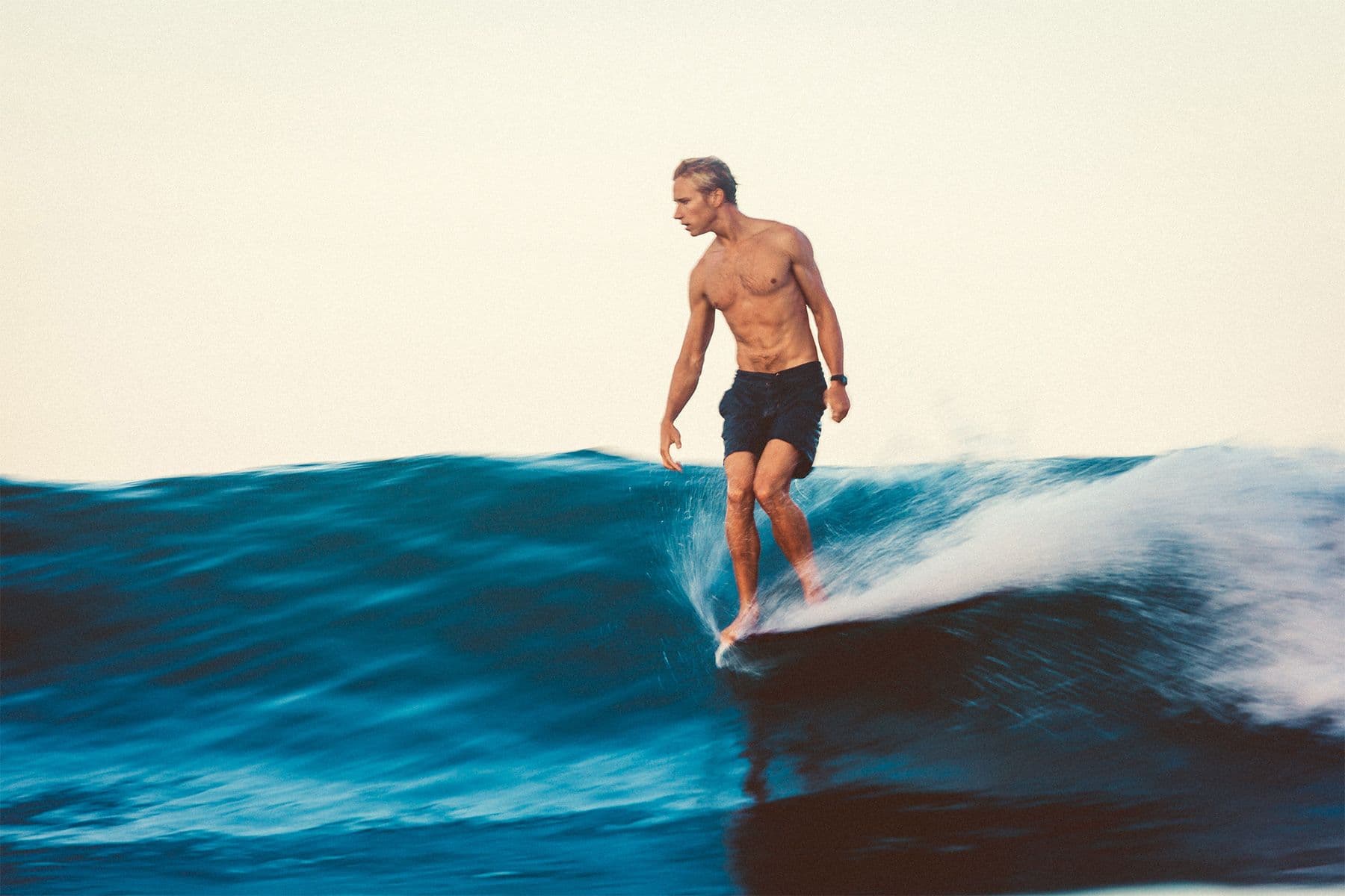 speed blur of surfer asher king perched on the nose of a longboard by saltshots