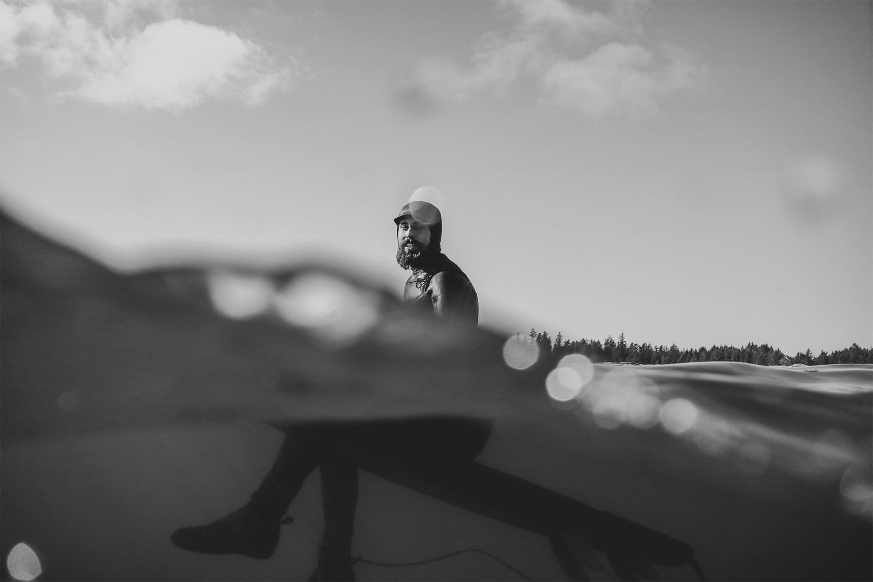 canadian architectural designer john fache sitting on his surfboard in the lineup waiting for a wave