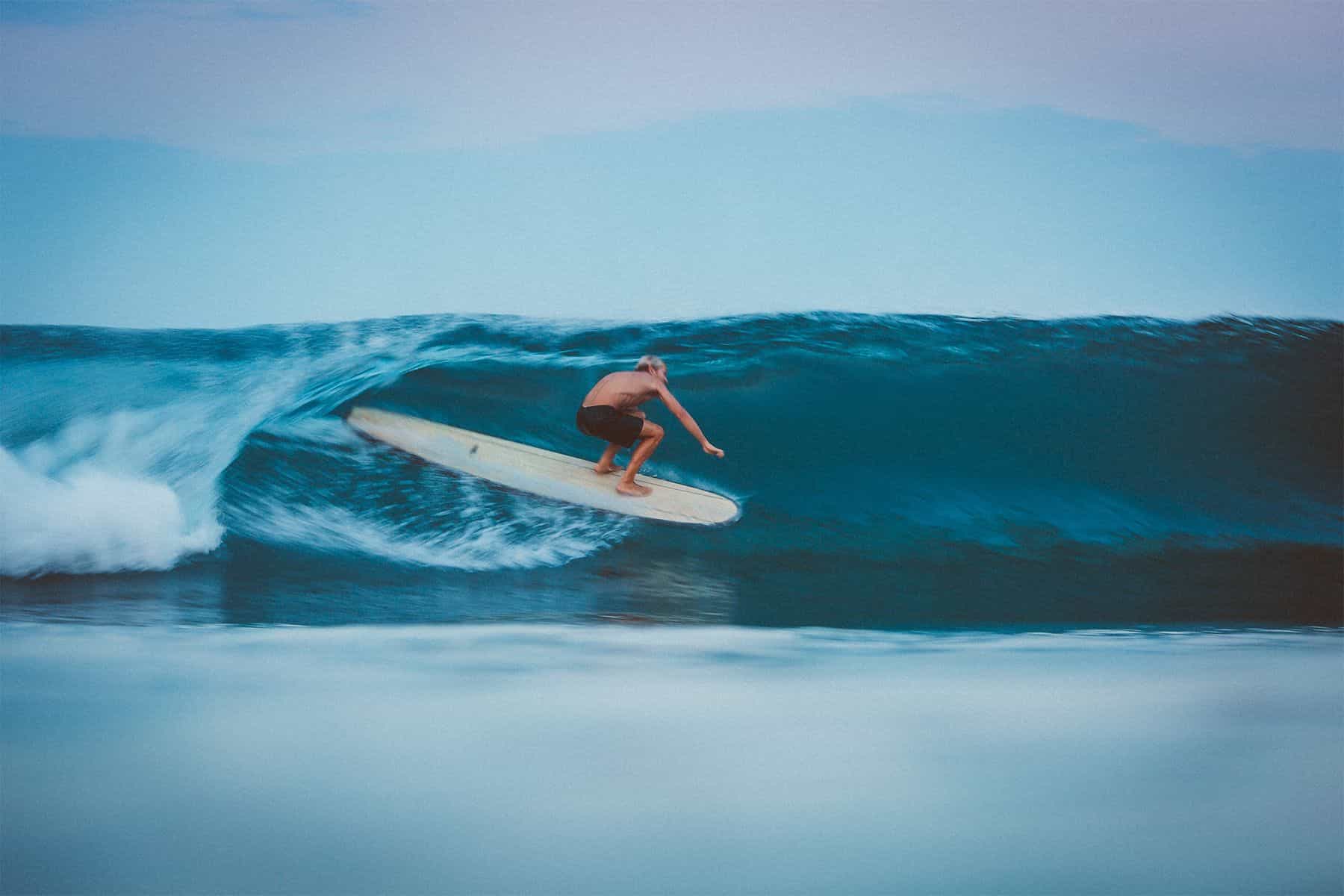 surfer asher king barrelled on a longboard at sunset by saltshots